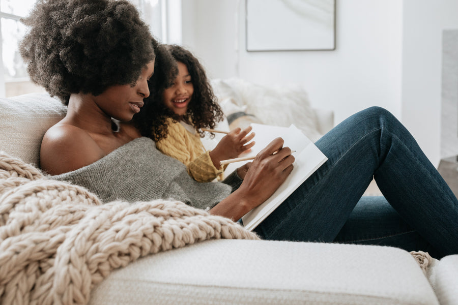 black mother sitting on a couch with her daughter | ade + ayo